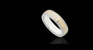 White and yellow gold patterned Men's Mokume Gane wedding ring displayed on a reflective black surface.