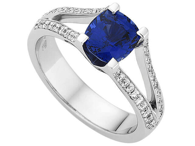 A Split Band With Ceylon Sapphire Ring C1200 featuring a mesmerizing Ceylon Sapphire set amongst sparkling diamonds, all encased in lustrous white gold.