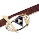 Meteor -1997 jewellery design award finalist – C4033, is a geometric abstract brooch featuring a wood-textured rectangular titanium bar, gold triangular elements, central trilliant cut diamond- that glistens like a meteor.