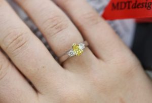 A woman's hand holding a Fancy Vivid Yellow Pear Shaped & Diamond Ring C990.