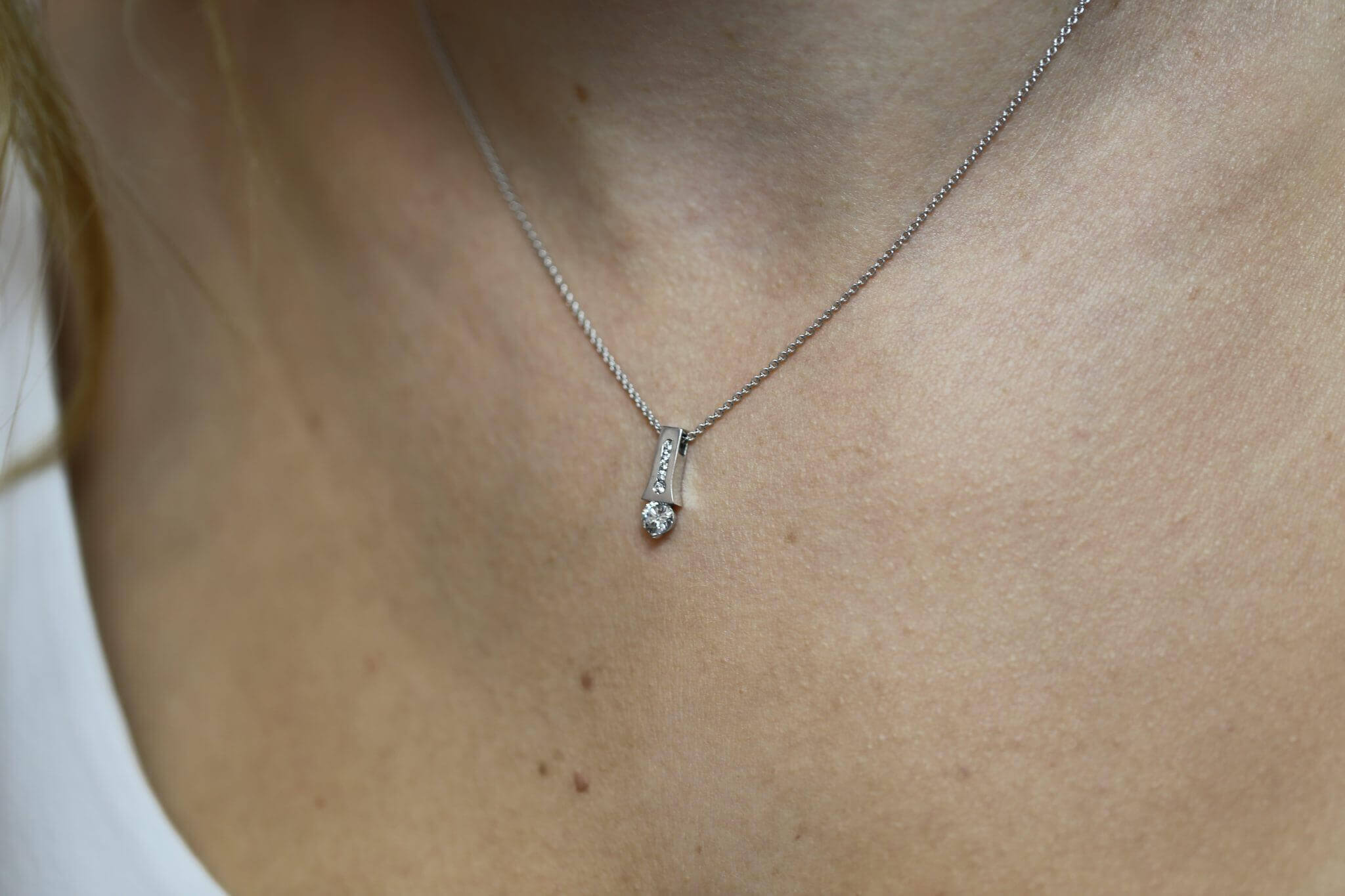 A close up of a woman's neck adorned with a White Gold Claw and Channel Set Pendant C1006A.