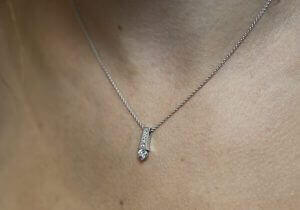 A close up of a woman's neck adorned with a White Gold Claw and Channel Set Pendant C1006A.