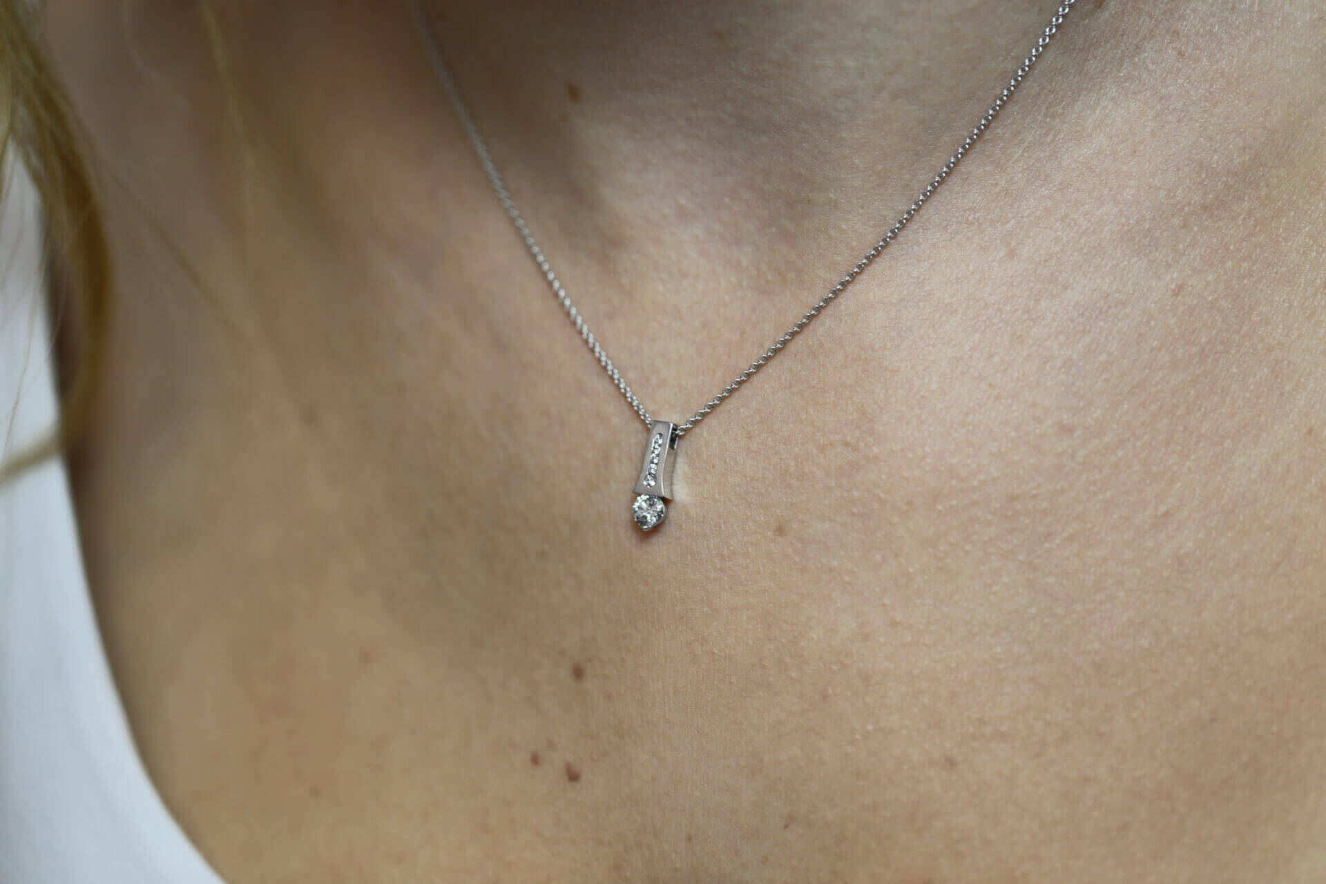 A close up of a woman's neck adorned with a White Gold Claw and Channel Set Pendant C1006A.