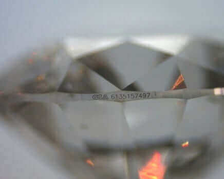 A close up view of a diamond featuring laser inscription.