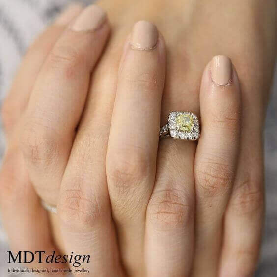 A woman's hand holding a Fancy Intense Yellow Cushion Cut Halo Diamond Ring C1005 engagement ring.
