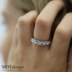 A woman's hand with a Wide Channel Set Round Diamonds Band C520 diamond ring on it.