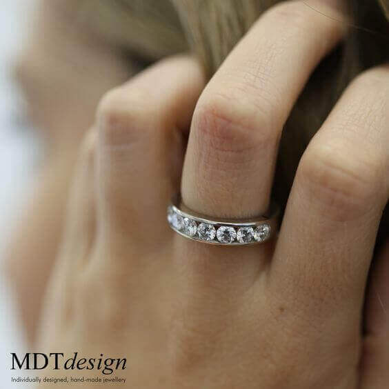 A woman's hand with a Wide Channel Set Round Diamonds Band C520 diamond ring on it.
