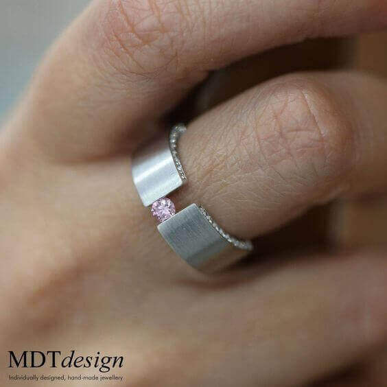 A woman wearing a Tension Set Pink Diamond Ring With Diamonds On Edge C827.