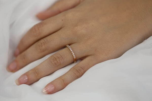 A woman's hand adorned with a dazzling Rose Gold Pink Diamond Wedding Ring C572-Pink, elegantly crafted in rose gold.