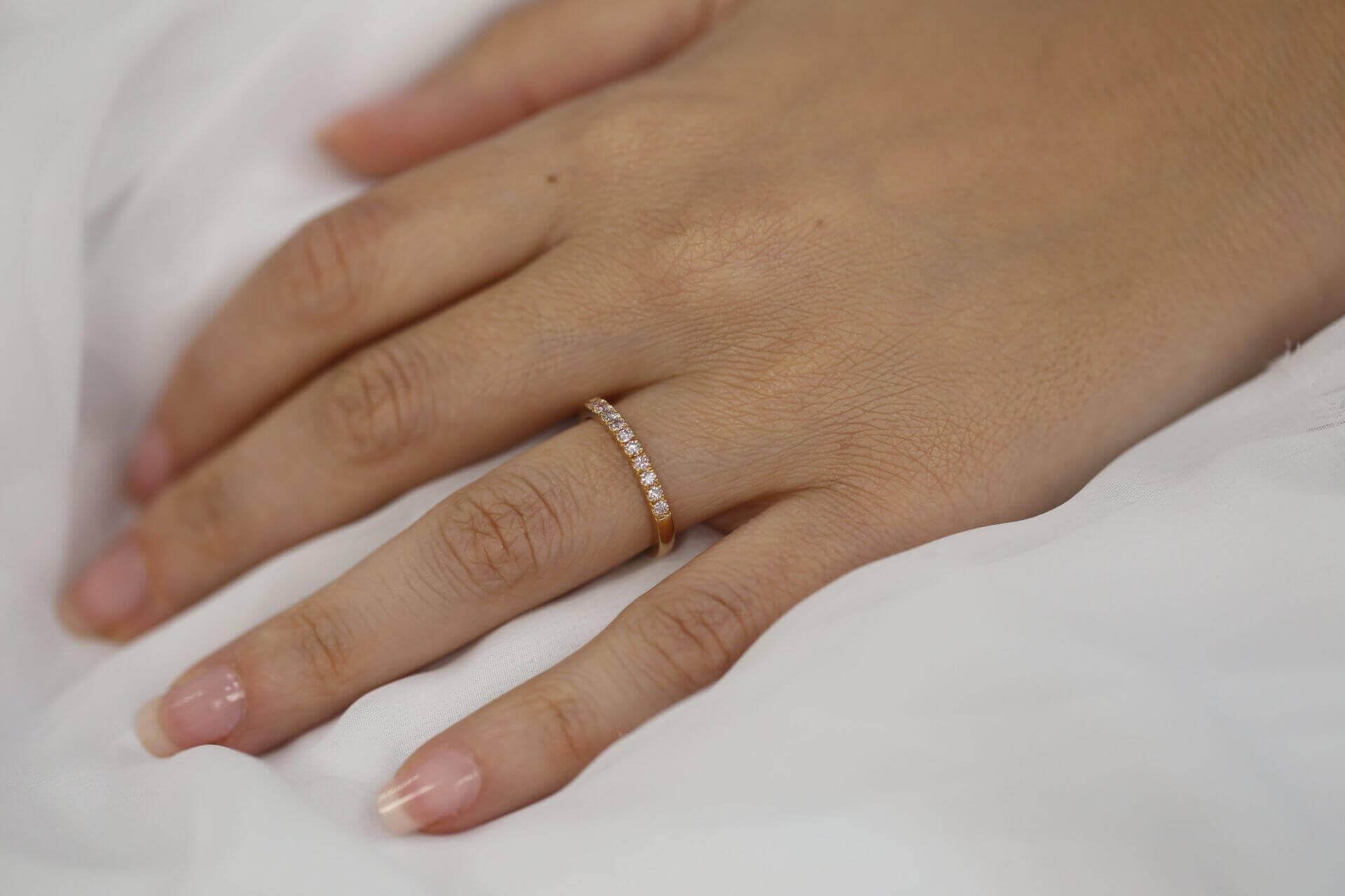 A woman's hand adorned with a dazzling Rose Gold Pink Diamond Wedding Ring C572-Pink, elegantly crafted in rose gold.