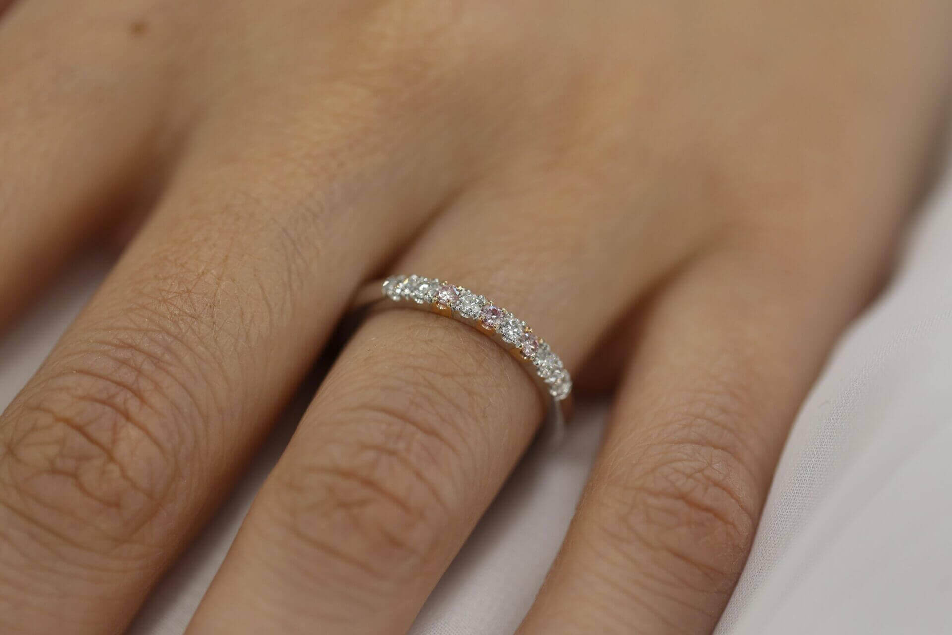 A woman's hand adorned with a stunning White and Pink Diamond Wedding Ring C573.