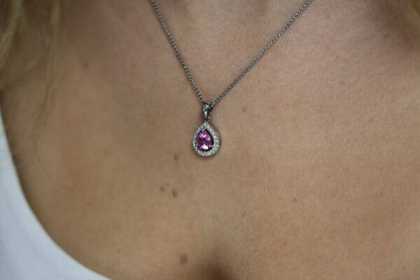 A close up of a woman with a Pink Sapphire and Diamond Halo Pendant C785.
