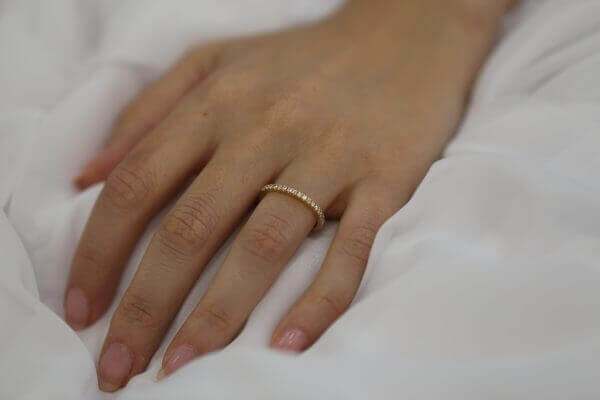 A woman's hand gracefully displaying a Yellow gold claw set diamond wedding ring C571.