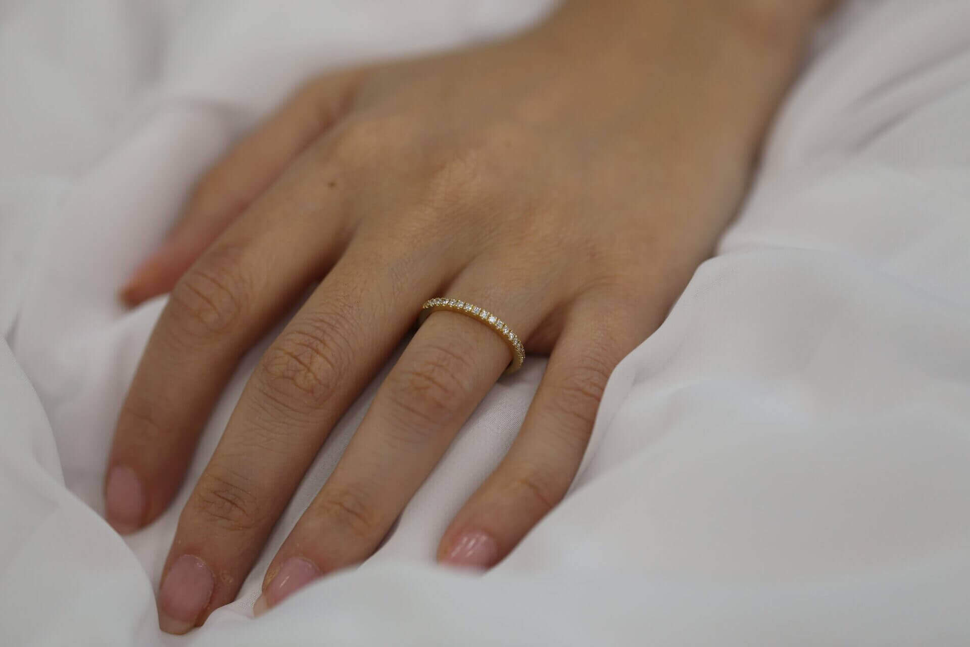A woman's hand gracefully displaying a Yellow gold claw set diamond wedding ring C571.