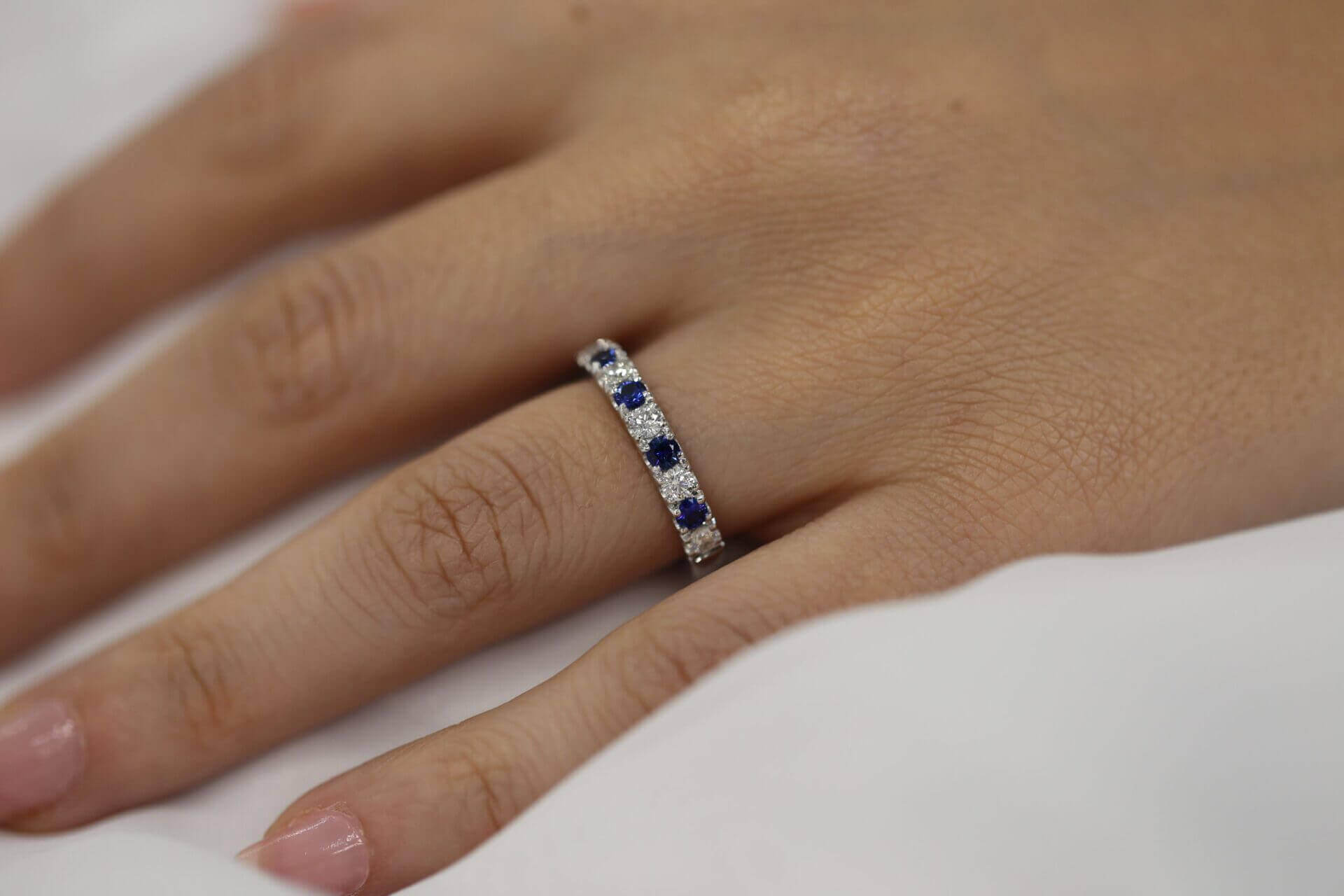 A woman's hand adorned with a Claw set Ceylon sapphire wedding ring C577 featuring a stunning Ceylon sapphire and diamond.
