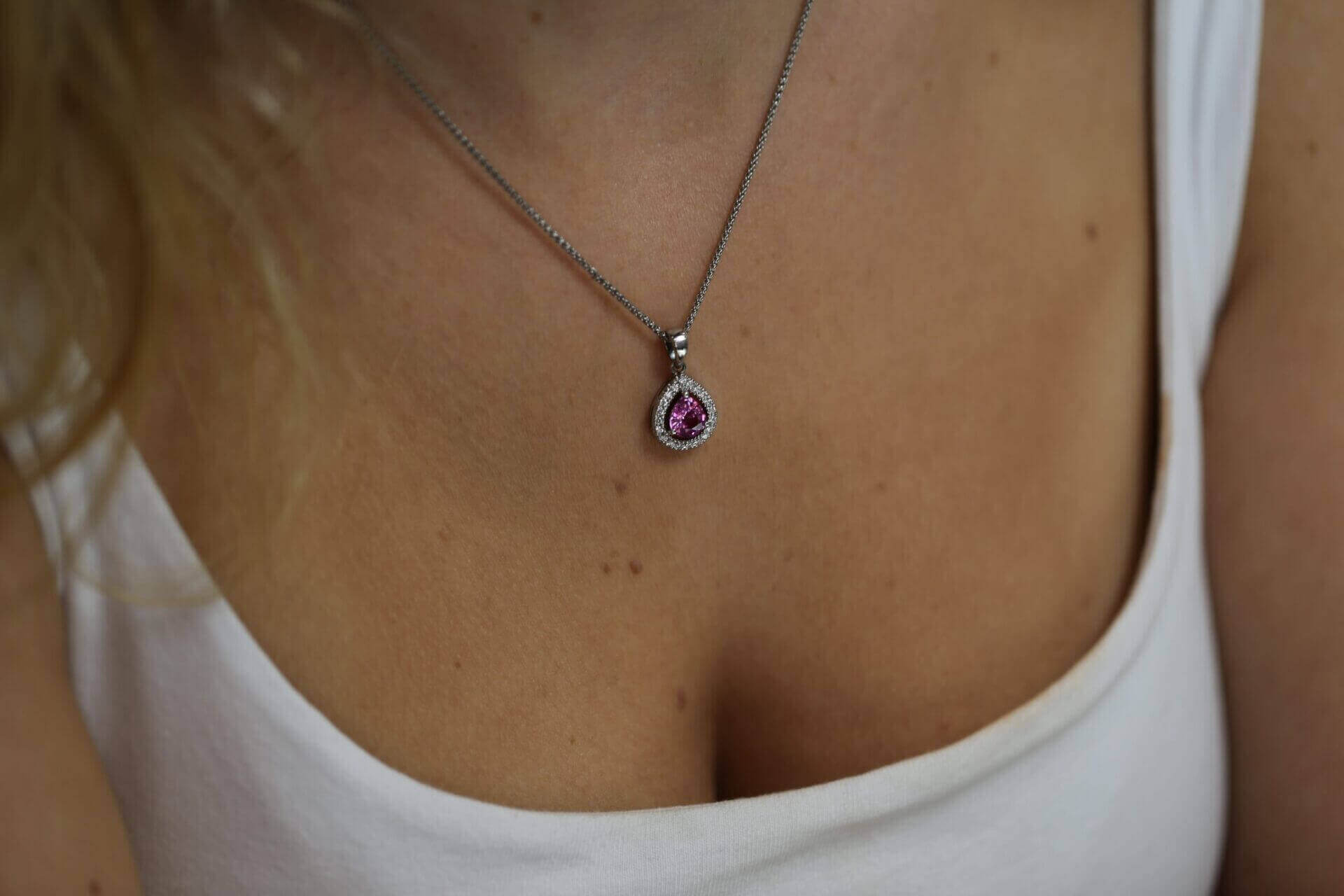 A woman wearing a Pink Sapphire and Diamond Halo Pendant C785.