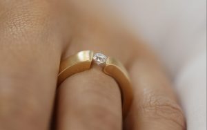 A woman wearing a Yellow Gold Flat Tension Set Round Diamond Ring C745 with a round diamond.