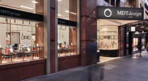 Exterior view of MDT design jewellery store in Melbourne, one of the finest local jewellery stores on Collins Street, with large glass windows displaying various pieces and a well-lit interior. The entrance is in the center, flanked by two large display windows.