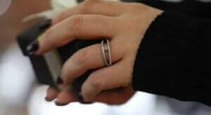 Close-up of a hand wearing the perfect engagement ring, with a gift box held in the other hand.