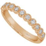 An 18k rose gold wedding band adorned with bezel set round diamonds.