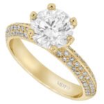 A stunning 18ct yellow gold engagement ring featuring a 2ct round brilliant cut diamond and pave diamond set shoulders