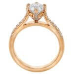 A stunning rose gold engagement ring with an oval cut diamond, featuring a hidden halo setting.