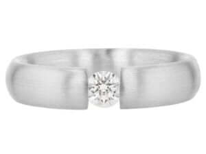 A white gold ring with a diamond tension set in the center.
