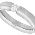 A tension set white gold ring with a round diamond in the center, polished finish