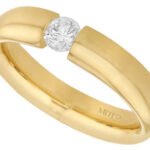 A yellow gold ring with a diamond in the center, beautifully tension set -polished finish