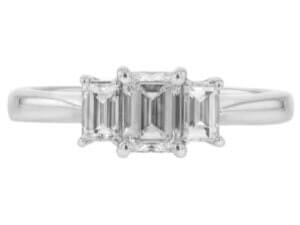 A stunning white gold engagement ring featuring a mesmerizing emerald cut diamond as the center stone, accompanied by two additional diamonds.