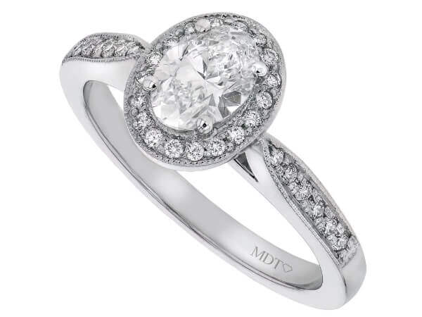 An oval diamond halo engagement ring in white gold featuring a grain set oval diamond.