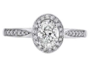 An oval diamond halo engagement ring in white gold, featuring a grain set diamond band. top view