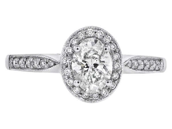 An oval diamond halo engagement ring in white gold, featuring a grain set diamond band. top view