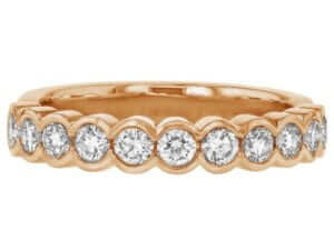 A stunning 18k rose gold wedding ring, featuring a half bezel set of round diamonds in an eternal band.