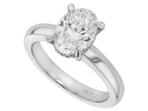 A white gold engagement ring with an oval cut diamond featuring a hidden halo.