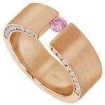 A rose gold tension set ring adorned with a captivating pink sapphire surrounded by sparkling diamonds.