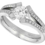 A white gold engagement ring with an oval cut diamond in a tension set.