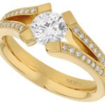 A stunning yellow gold engagement ring featuring an oval cut diamond on a split band.