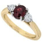 yellow Gold ring with oval ruby centre flanked by round white diamonds.