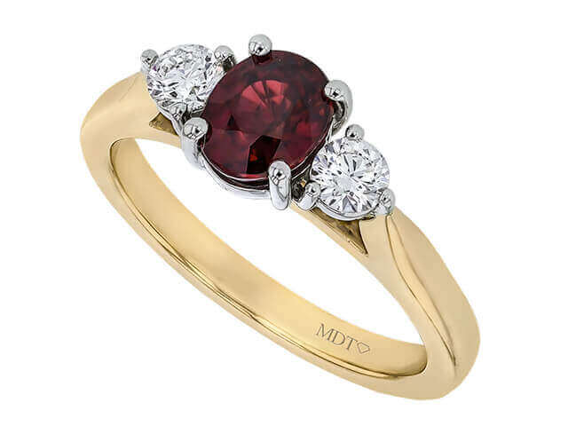 yellow Gold ring with oval ruby centre flanked by round white diamonds.