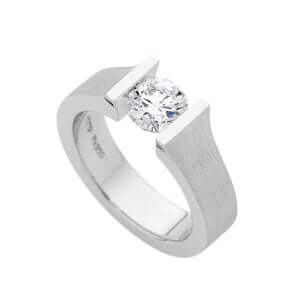 c957, a photograph of a floating diamond tension set engagement ring, with a white diamond and platinum metal. 
