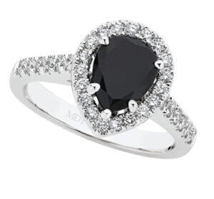 A unique engagement ring featuring a pear-shaped black diamond surrounded by small white diamonds, with additional diamonds encrusted along the band. A classic halo design mixed with contemporary style resulting in a unique engagement ring