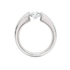 A minimalist ring with a single diamond held by a sleek, modern setting, viewed from the side. This piece is part of MDTdesign's collection of unique engagement rings and tension set designs 
