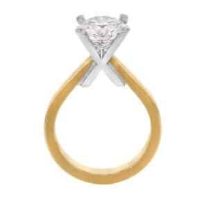 An engagement ring with a gold band and a round diamond solitaire set in a white gold x prong setting, perfect for those seeking unique engagement rings.