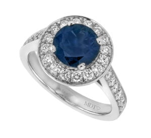 A white gold halo engagement ring with a large blue australian sapphire in the centre, surrounded by smaller white gemstones set in a circular design.