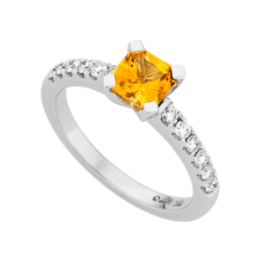 A white gold engagement ring with a large yellow sapphire gemstone in the centre, flanked by smaller clear stones set along the band, reminiscent of the stunning sapphire engagement rings popular in Melbourne.
