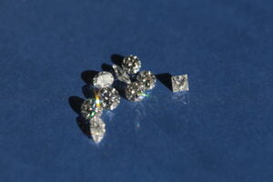 A blue background featuring an array of different shaped natural diamonds scattered randomly