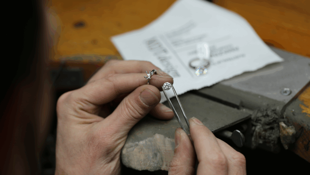 Close-up of diamond setting process, jeweller holding a diamond and ring setting in MDT DESIGN’s handmade jewellery workshop.