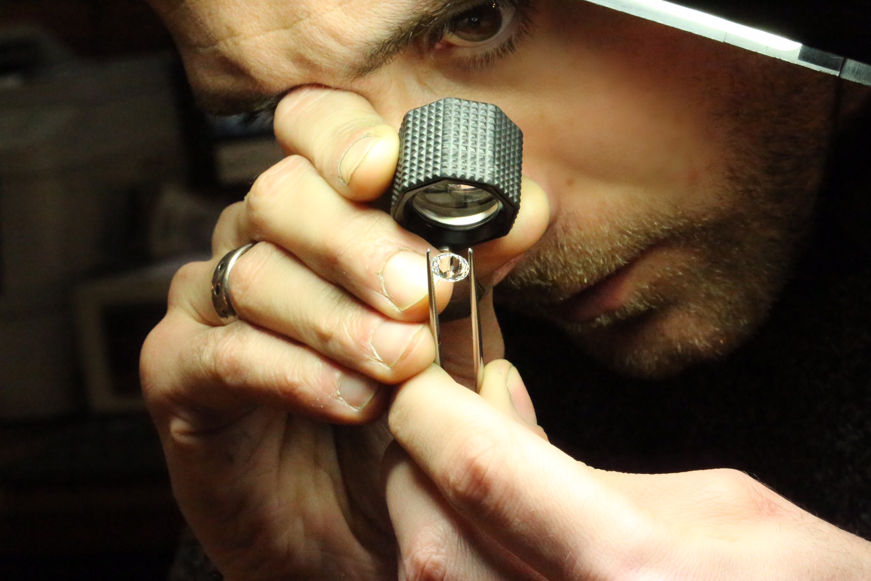 Jewellery inspecting a natural diamond through an eyeglass