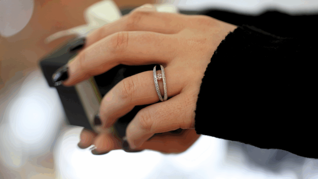 Hand holding MDT DESIGN box, showcasing a diamond tension set split band ring with a pink diamond